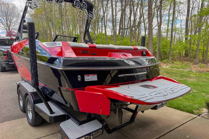 Slide: The Image of 2016 Axis A22 boat with red and black design on a trailer in a wooded area. - 8