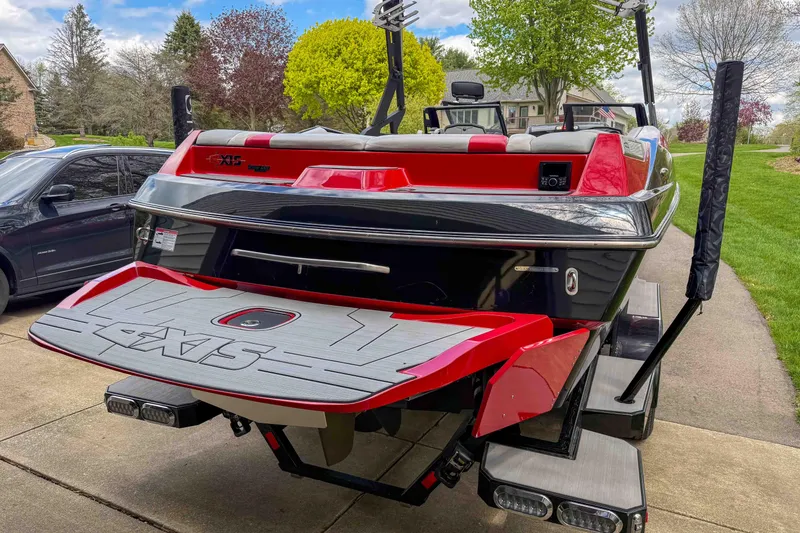 Slide: The Image of 2016 Axis A22 boat with red and black design, parked on a driveway. - 9
