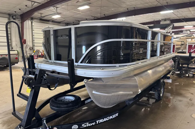 The Image of 2026 Sun Tracker Party Barge 16 DLX pontoon boat in a warehouse setting. - 1