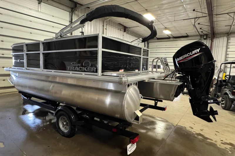 Slide: The Image of 2026 Sun Tracker Party Barge 16 DLX pontoon boat with Mercury outboard motor in a garage. - 4
