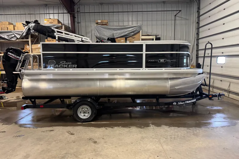 Slide: The Image of 2026 Sun Tracker Party Barge 16 DLX pontoon boat in a garage setting. - 5