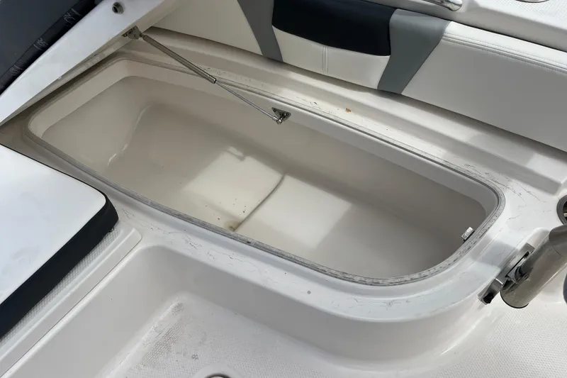 Slide: The Image of 2024 Robalo 226 Cayman boat storage compartment, open and empty, with cushioned seating nearby. - 15