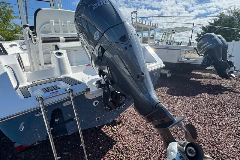 Slide: The Image of 2026 Tidewater 220 CC Adventure boat with powerful outboard motor in a sunny marina. - 2