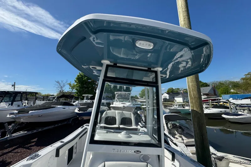 Slide: The Image of 2026 Tidewater 220 CC Adventure boat with T-top, docked under clear blue sky. - 20