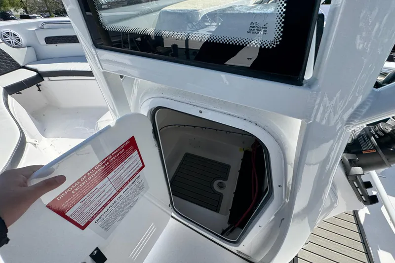 Slide: The Image of 2026 Tidewater 220 CC Adventure boat storage compartment with open hatch and safety instructions. - 28