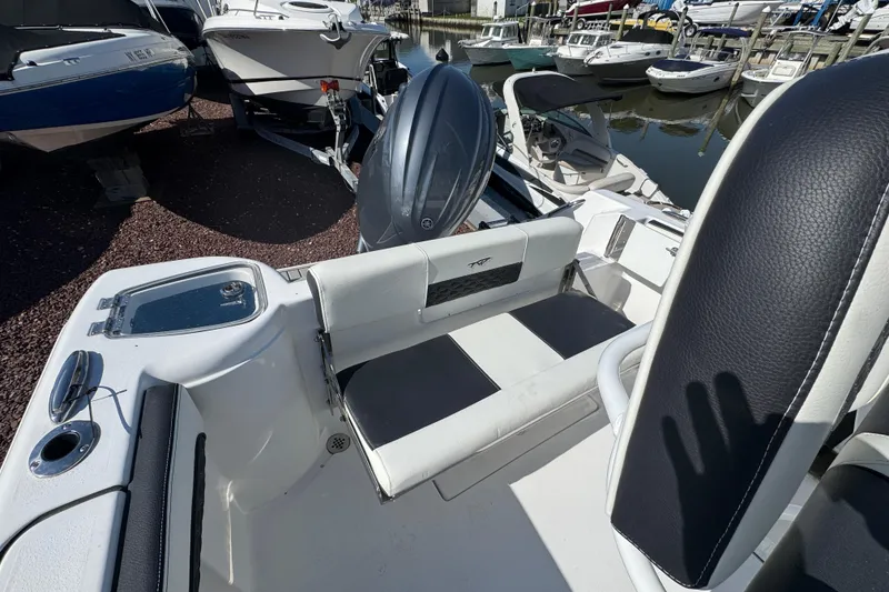 Slide: The Image of 2026 Tidewater 220 CC Adventure boat interior with seating and motor, docked at marina. - 3