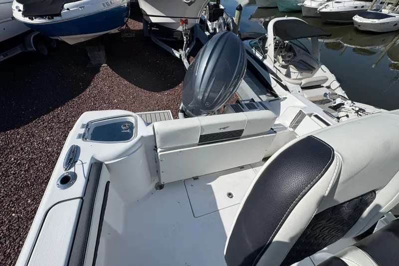 Slide: The Image of 2026 Tidewater 220 CC Adventure boat interior with seating and motor, docked among other boats. - 4