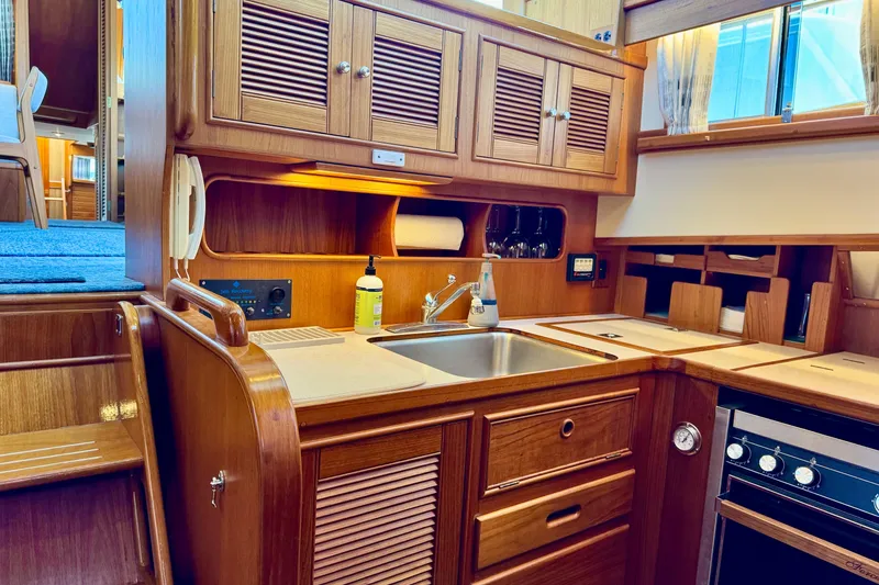 Slide: The Image of Interior of 1996 Grand Banks 46 Heritage CL yacht, featuring a wooden kitchen with sink and stove. - 38