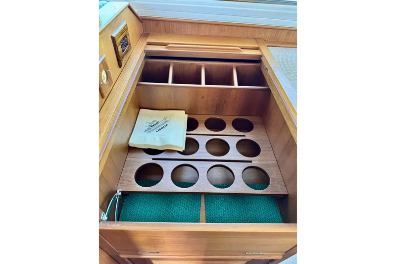 Slide: The Image of Wooden storage compartment on 1996 Grand Banks 46 Heritage CL yacht, featuring circular cutouts and a napkin. - 40