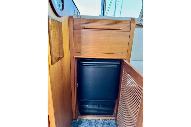 Slide: The Image of Wooden cabinetry with a compact fridge inside a 1996 Grand Banks 46 Heritage CL yacht. - 53