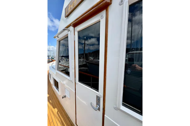 Slide: The Image of Side view of 1996 Grand Banks 46 Heritage CL yacht with wooden trim and reflective windows. - 76
