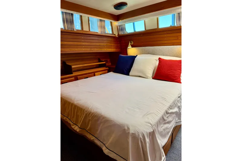 Slide: The Image of Cozy bedroom in 1996 Grand Banks 46 Heritage CL yacht with wooden paneling and colorful pillows. - 90