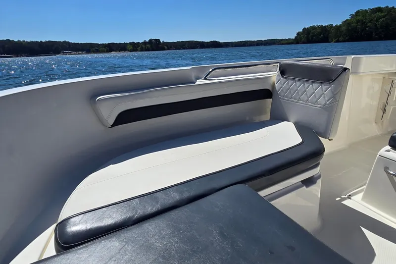 Slide: The Image of 2023 Bayliner Trophy T22CC boat interior with cushioned seating on a sunny day. - 11