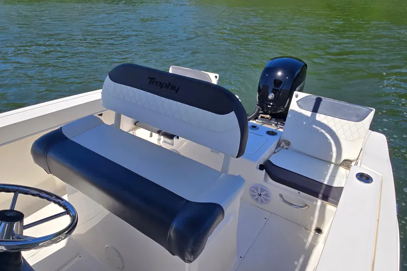 Slide: The Image of 2023 Bayliner Trophy T22CC boat interior with seating and motor on a calm lake. - 14