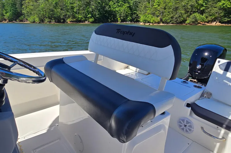 Slide: The Image of 2023 Bayliner Trophy T22CC boat interior with steering wheel and seating, on a scenic lake. - 15