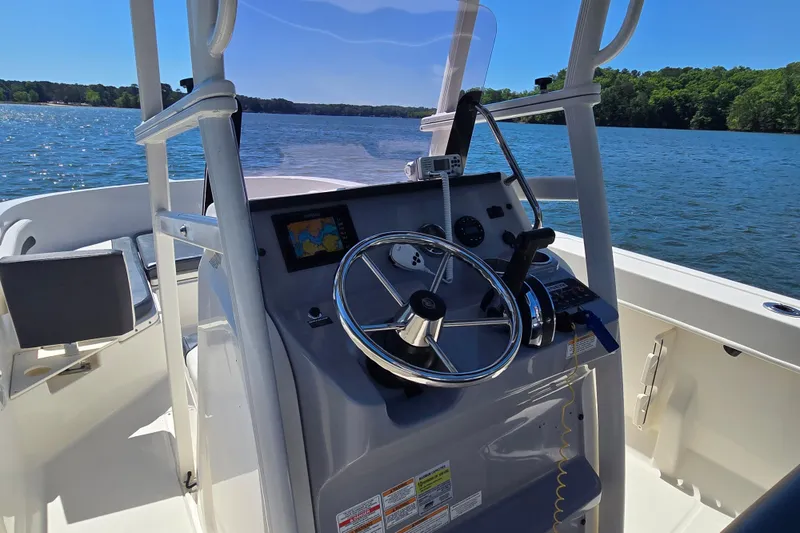 Slide: The Image of 2023 Bayliner Trophy T22CC boat dashboard with steering wheel, on a sunny lake. - 16