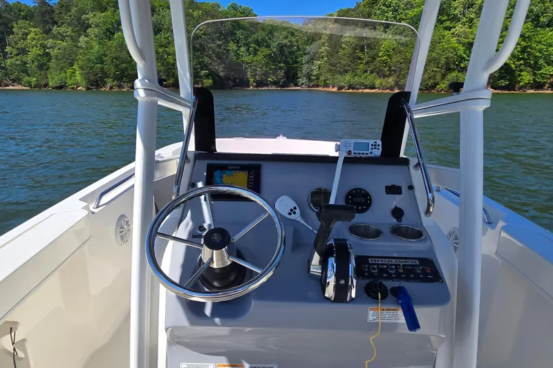 Slide: The Image of 2023 Bayliner Trophy T22CC boat dashboard with steering wheel and controls on a lake. - 17