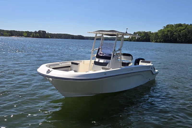 Slide: The Image of 2023 Bayliner Trophy T22CC boat on a serene lake under clear blue skies. - 3