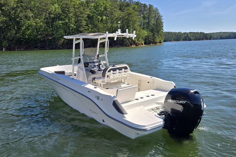 Slide: The Image of 2023 Bayliner Trophy T22CC boat on a serene lake with lush forest backdrop. - 6