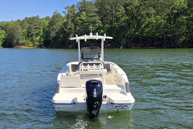 Slide: The Image of 2023 Bayliner Trophy T22CC boat on a serene lake with lush forest backdrop. - 7