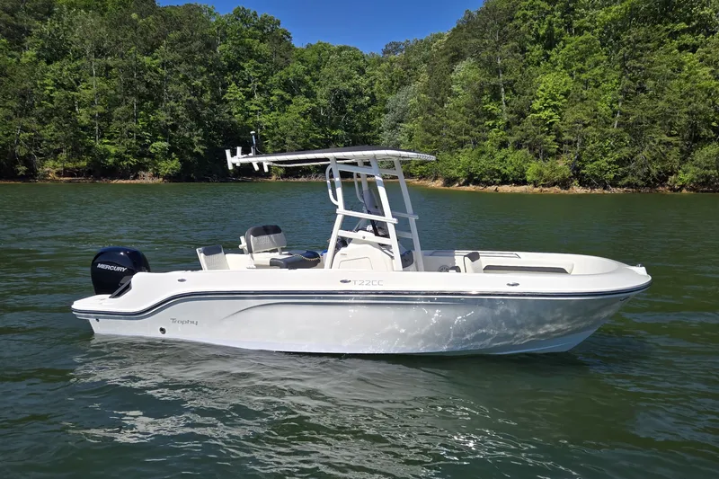 Slide: The Image of 2023 Bayliner Trophy T22CC boat on a serene lake with lush green forest backdrop. - 9