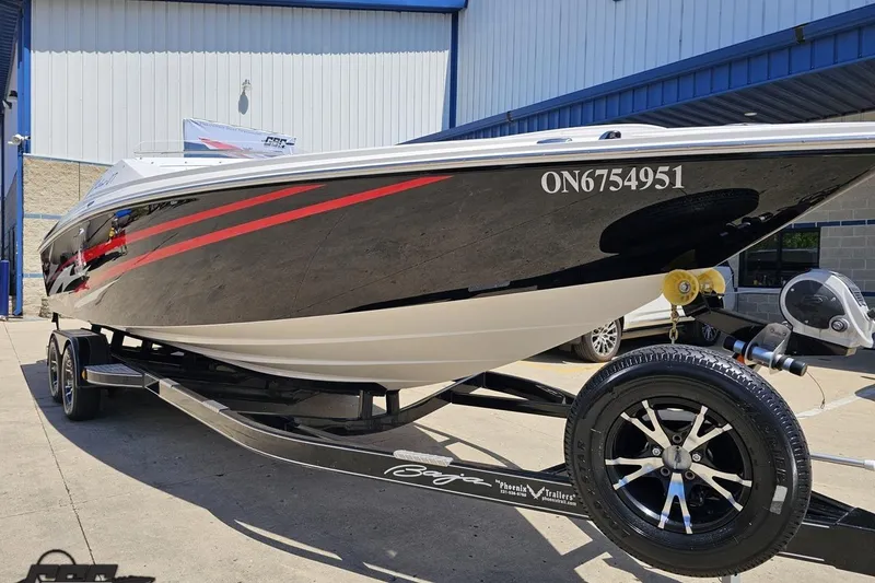 Slide: The Image of 2019 Baja 27 Outlaw boat on trailer, black with red accents, parked outdoors. - 12