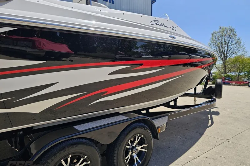 Slide: The Image of 2019 Baja 27 Outlaw boat with sleek red and black graphics on a trailer. - 8