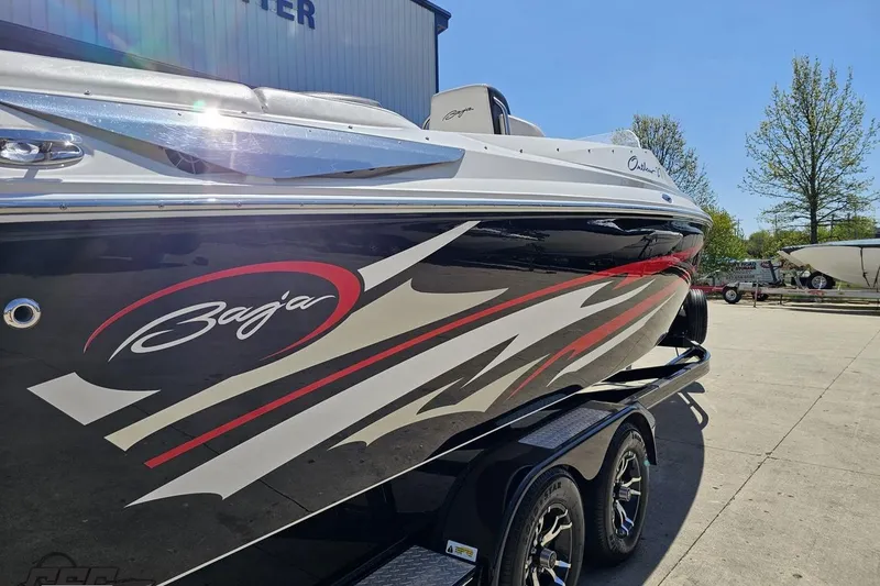 Slide: The Image of 2019 Baja 27 Outlaw boat with sleek graphics on a trailer in a sunny outdoor setting. - 9