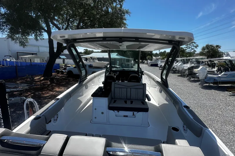 Slide: The Image of 2026 Monterey Elite 30 OB boat interior with seating and helm, parked outdoors. - 5
