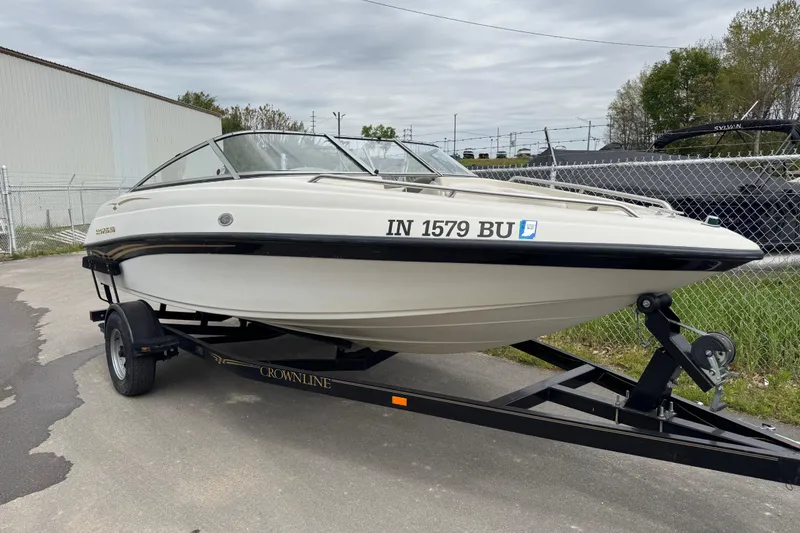 The Image of 2000 Crownline 180 BR boat on trailer, parked outdoors near a fence. - 0