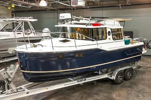 The Image of 2025 Ranger Tug R23 Luxury Edition boat on trailer in indoor showroom. - 1