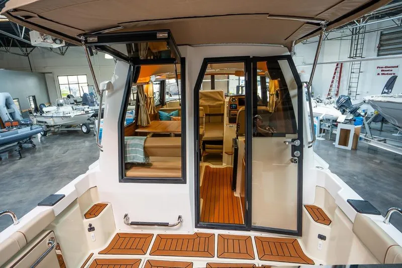 Slide: The Image of 2025 Ranger Tug R23 Luxury Edition interior view with teak flooring in a showroom. - 10