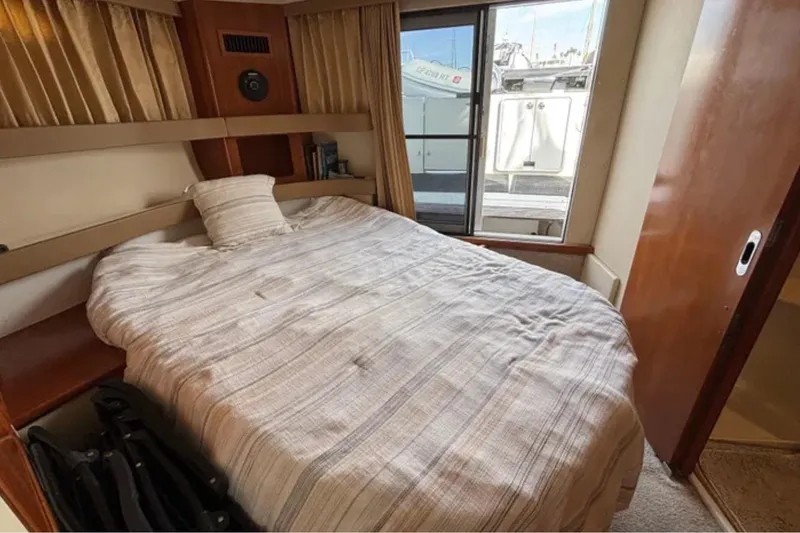 Slide: The Image of Cozy bedroom in 2005 Carver 41 Cockpit Motor Yacht with window view and striped bedding. - 3