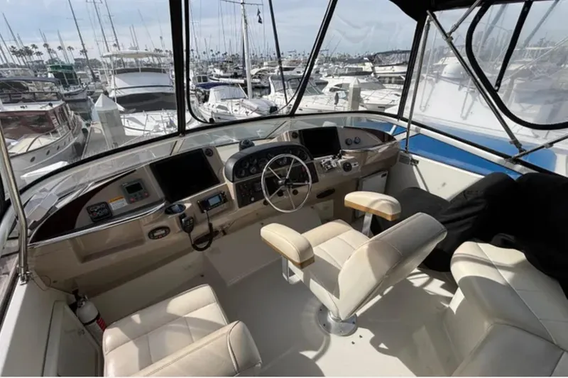 Slide: The Image of 2005 Carver 41 Cockpit Motor Yacht helm with marina view, featuring modern controls and seating. - 8