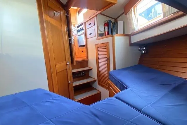 Slide: The Image of Interior of 2000 Grand Banks 36 Classic yacht with blue bedding and wooden cabinetry. - 14