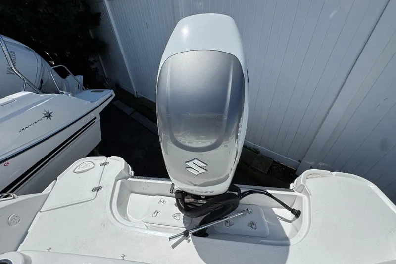 Slide: The Image of 2026 Stingray 259 DC boat with Suzuki outboard motor, docked beside another vessel. - 13