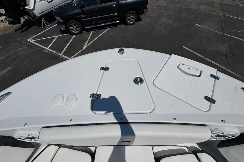Slide: The Image of 2026 Stingray 259 DC boat deck with storage compartments, parked near a black truck. - 33