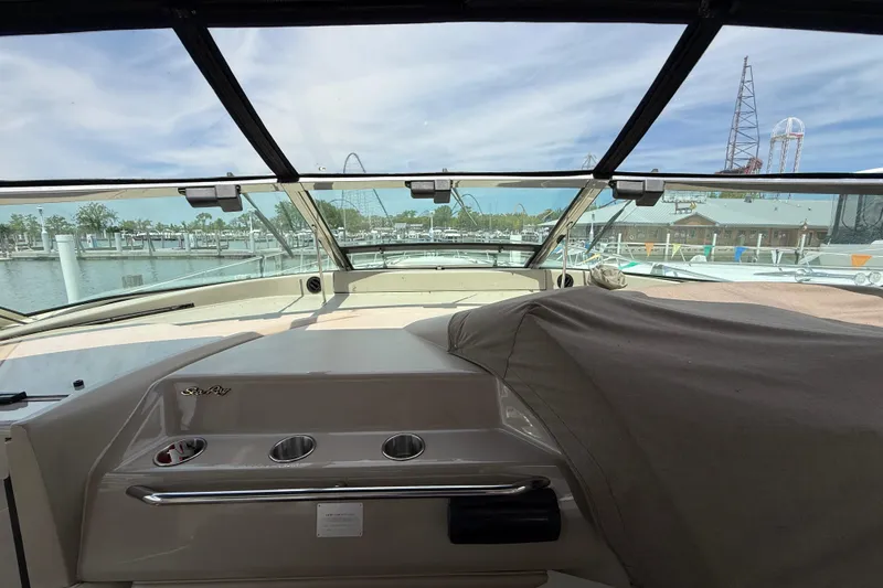 Slide: The Image of 1998 Sea Ray 500 Sundancer cockpit view with marina backdrop and clear skies. - 23
