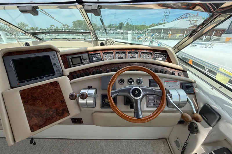 Slide: The Image of 1998 Sea Ray 500 Sundancer helm with wood accents, steering wheel, and navigation instruments. - 24