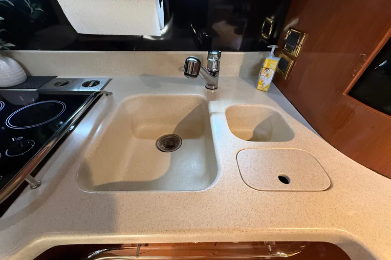 Slide: The Image of Kitchen sink area in a 1998 Sea Ray 500 Sundancer yacht, featuring dual basins and a stovetop. - 56