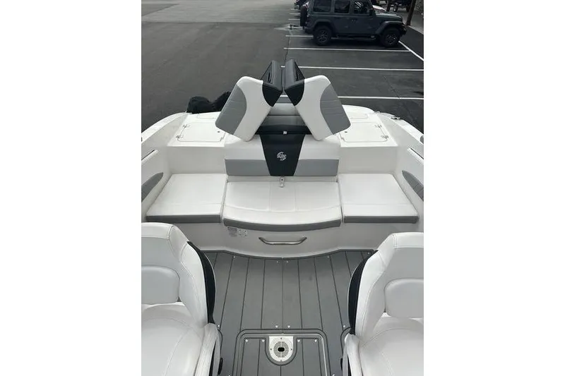 Slide: The Image of 2021 Chaparral 21 Surf boat interior with white and gray seating, parked in a lot. - 11