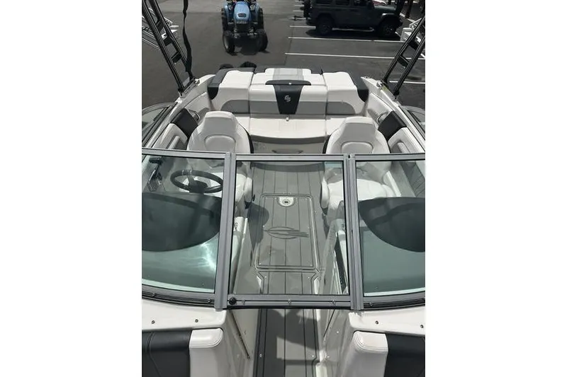 Slide: The Image of 2021 Chaparral 21 Surf boat interior with seating and steering wheel, parked in a lot. - 12