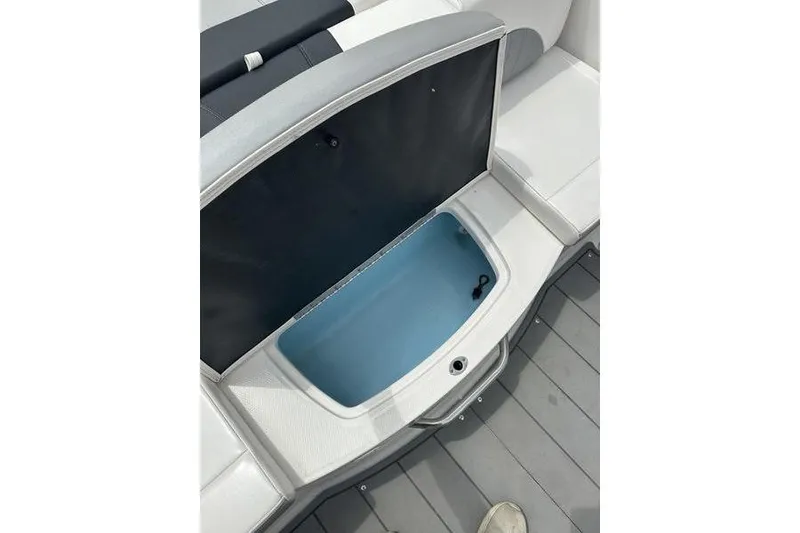 Slide: The Image of 2021 Chaparral 21 Surf boat storage compartment with open lid, showcasing interior space. - 18