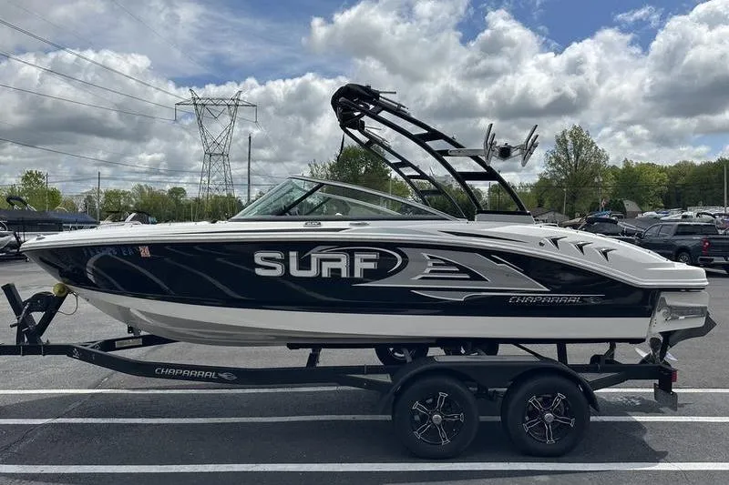 Slide: The Image of 2021 Chaparral 21 Surf boat on trailer, parked outdoors under cloudy sky. - 7