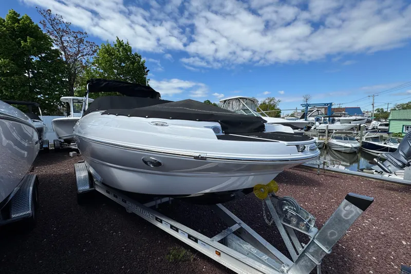 The Image of 2026 Stingray 231 DC boat on trailer, docked at marina under blue sky. - 1