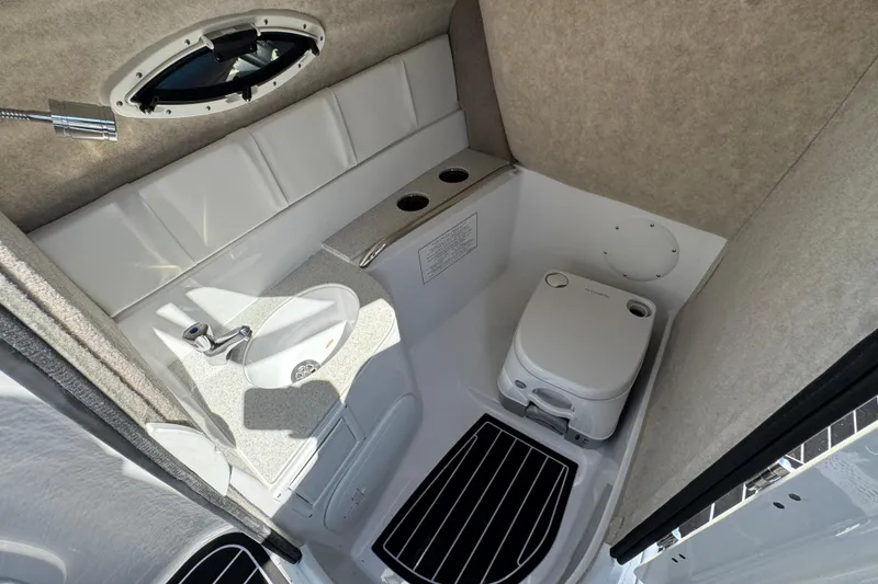 Slide: The Image of 2026 Stingray 231 DC boat interior with compact bathroom, featuring sink and portable toilet. - 20