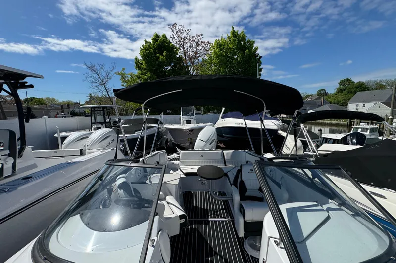 Slide: The Image of 2026 Stingray 231 DC boat with canopy, docked among other boats under a clear sky. - 29