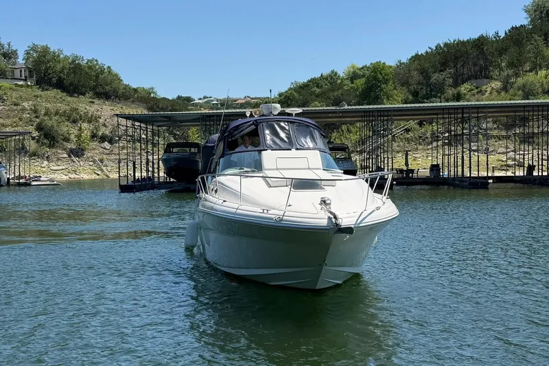 Slide: The Image of 2006 Sea Ray Sundancer 320 yacht cruising on a serene lake near a dock. - 10