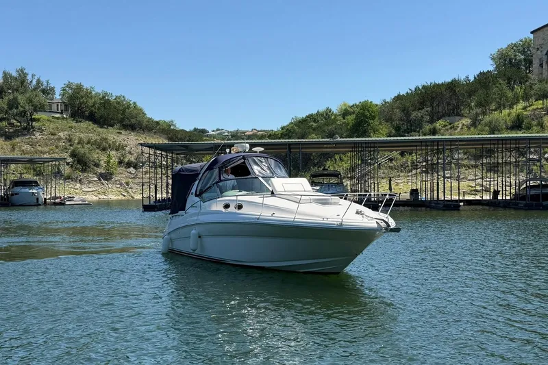 Slide: The Image of 2006 Sea Ray Sundancer 320 yacht cruising on a serene lake near a marina. - 11