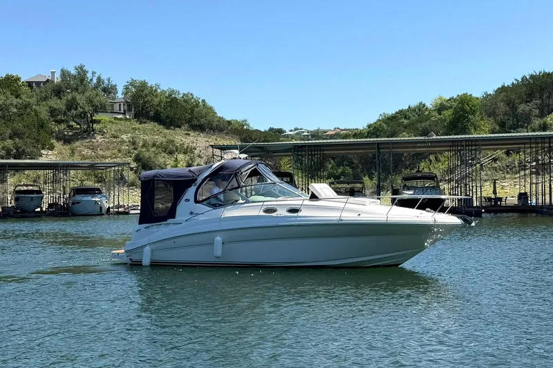 Slide: The Image of 2006 Sea Ray Sundancer 320 boat on a serene lake with docked boats in the background. - 12